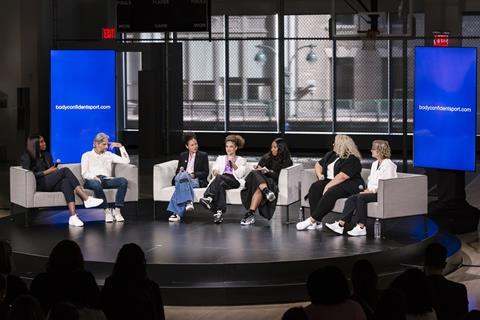 A panel of seven experts and athletes sit on stage during the launch event of the Body Confident Sport online coaching program on October 24, 2023. From left to right: Tennis champion and entrepreneur Venus Williams, Dove CMO Alessandra Manfredi, Nike Chi