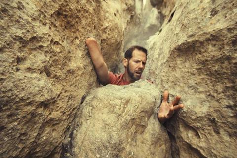 A climber scaling a rock face, using his remaining hand and adaptive technique; still image from a Columbia brand spot about accessible outdoor experiences